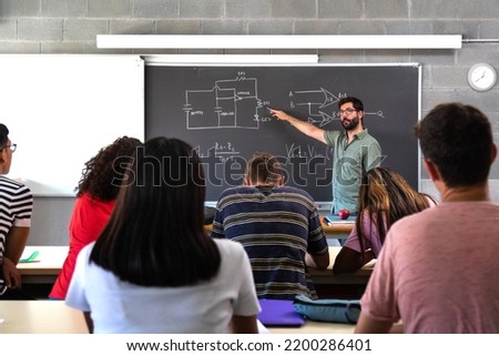 Male caucasian teacher explaining electronics and physics to multiracial high school students. Photo stock © 