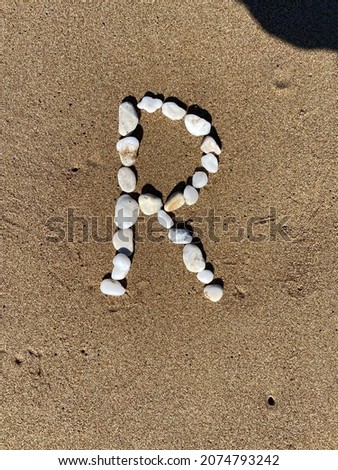the letter 'R' made of white pebbles on the sand Photo stock © 