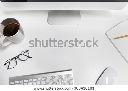 Empty workspace on white table. View from above on the clean, well organized working space framed by PC, keyboard, mouse, pencil, coffee cup and glasses