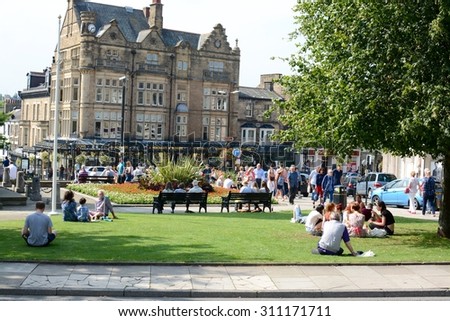 HARROAGTE, UK - AUGUST, 23 2015 -  People sat down on the grass, with the famous Bettys tea rooms in the background in Harrogate, Yorkshire, UK