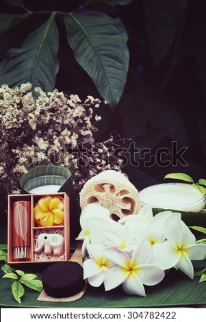 Thai Massage and Spa Concept in vintage style. Spa setting with coffee grounds and cream, Aroma oil and Plumeria flowers on banana leaf