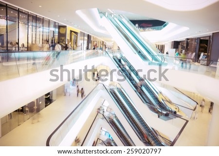 People in motion in escalators at the modern shopping mall.Defocused blur background.