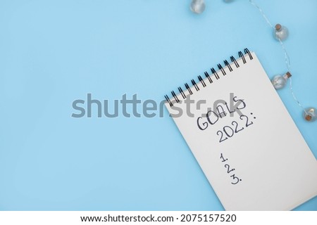 Notebook with text GOALS 2022 on  blue background. Motivation, inspiration. Planning, plans and tasks. New business ideas. Setting goal, target.