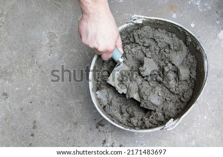 Mixing of concrete mortar.The builder prepares the cement mortar using a construction trowel.Plaster mortar in a bucket. Stockfoto © 