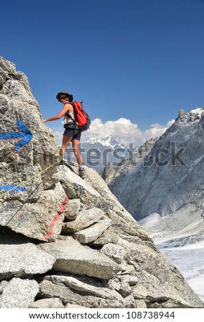 a slim, sporty girl, hiking in the high mountains, above a glacier on a beautiful sunny day