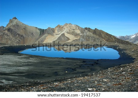 A lake at 10000 feet in the Swiss Alps. Picture taken facing west. In the foreground a very shallow lake, nearlysilted up  reflecting the mountinas behind.