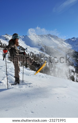 girl kicking powder snow in the air with a snow shoe