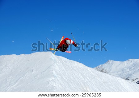 a skier with crossed ski landing on a jump ramp with crossed skis and with a horizontal body position and flashes of snow in the air