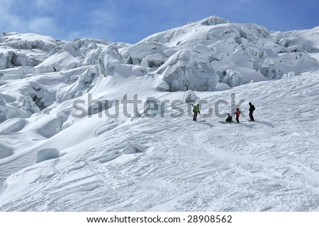 4 skiers on a large ice fall. blocks of blue ice can be seen clearly from under a mantel of fresh snow