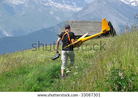 a model airplane enthusiast returning home through the meadows in the mountains with his plane