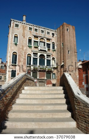 steps on a bridge over a canal in venice leading to a large italianate house with a tower