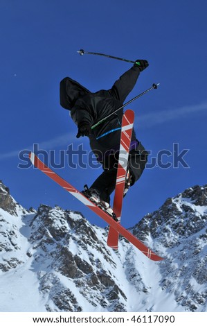 a freerider skier with crossed skis during a jump