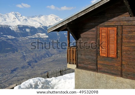 a mountain cabin surrounded by snow with a view over mountains and valleys
