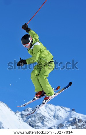 a freestyle ski jumper in green clothes performing a high jump