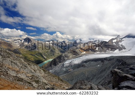 View from Switzerland to the Monte Moro pass (centre) into Italy including the Stausee and the Allalin glacier on a cloudy day in summer
