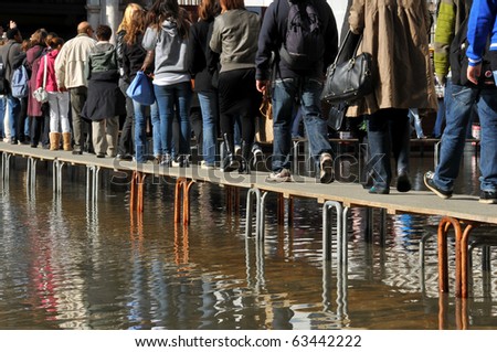 VENICE, ITALY - OCTOBER 20: Venice sinking beneath the sea, people walk on duckboards as sea water floods St Marks square:  October 20, 2010 in Venice Italy