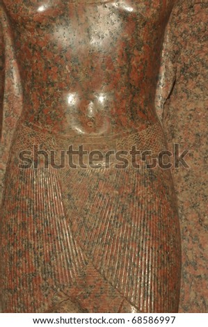 beautiful ancient egyptian sculpture in polished red granite of a woman\'s body with figure hugging skirt and naked chest