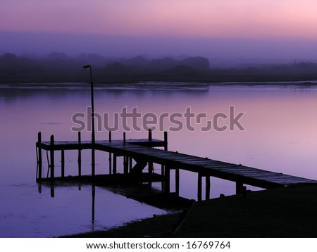 Beautiful low light view of a jetty on a river with reflections and in a purple color.