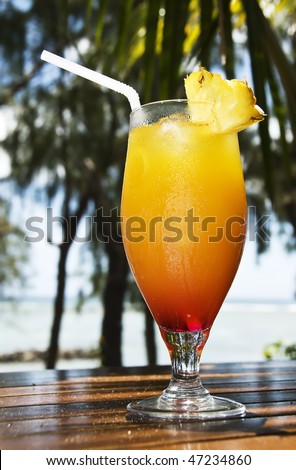 a Fresh ice cold fruit cocktail with sea and palm trees in the background