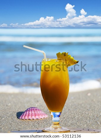 a Fresh fruit cocktail and aa sea shell on a tropical island beach