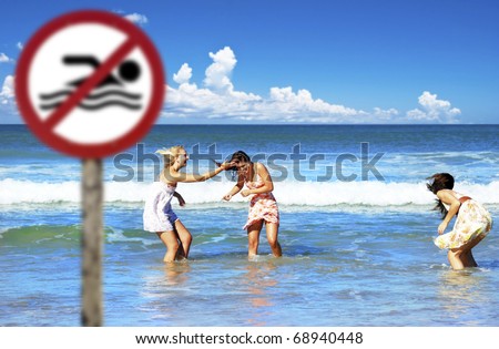 Three woman playing in the sea on a beach where swimming is no allowed - focus on the woman