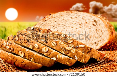Healthy sliced whole wheat bread with the sun going down over a green wheat field