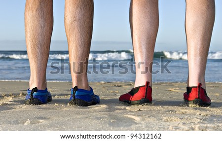 The calves and feet with shoes of two men on the beach in late afternoon sunlight