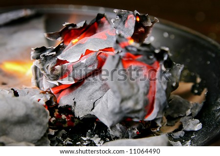 ball of burning paper among the ashes with flames