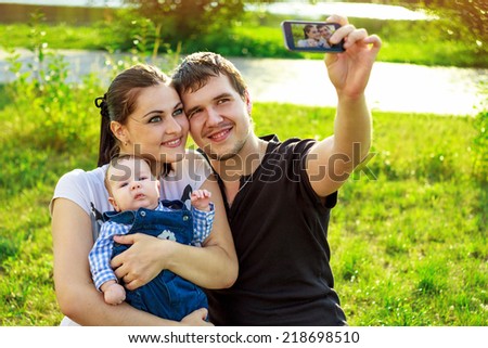 Family with baby In Park taking selfie by mobile phone