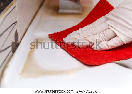 Hand in glove cleans dirty washbasin red sponge
