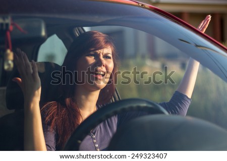Closeup portrait, angry young sitting woman pissed off by drivers in front of her and gesturing with hands. Road rage traffic jam concept