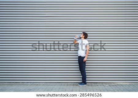 The young man drinks water on a metallic background
