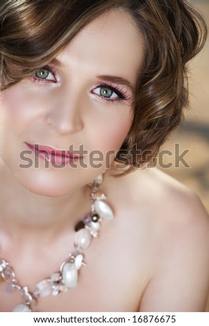 Young woman with pink make-up and green eyes in semi-precious stones necklace