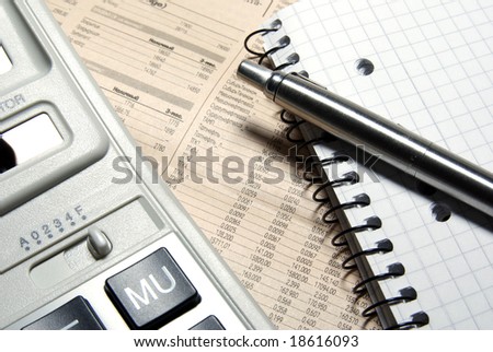 Financial calculator, steel pen and notebook laying on newspaper. Concept.