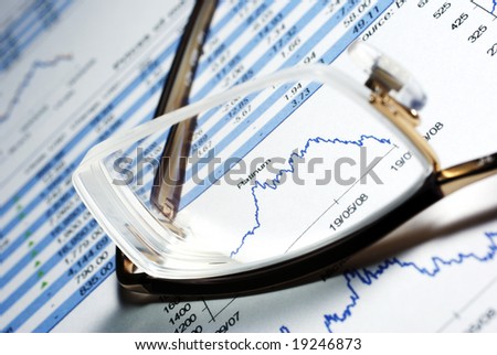 Glasses and printed financial report with data, charts.