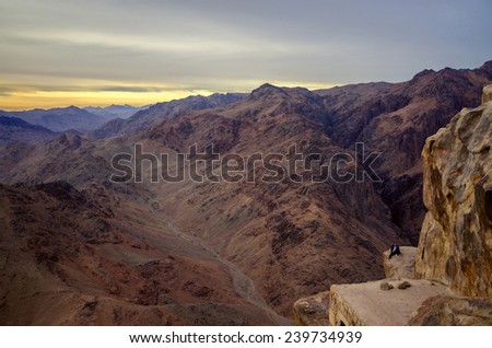 SINAI MOUNTAINS, EGYPT - NOVEMBER 28, 2013: Unidentified man are sitting on the edge of a cliff in the mountains of the Sinai, Egypt