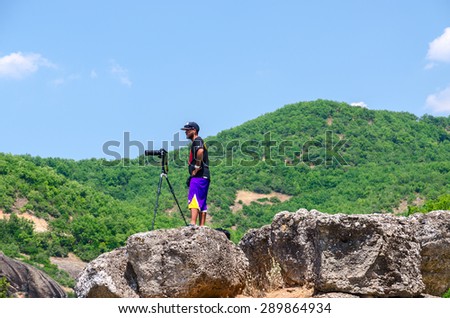 METEORS, GREECE - AUGUST 11, 2014: Unknown male photographer with photo camera on a tripod stands on the stones in Meteors, Greece