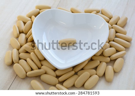 A pill in the white cup on the wooden background