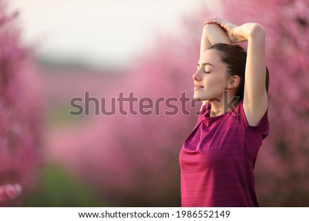 Relaxed runner stretching arms after exercise in a pink flowered field 商業照片 © 