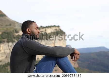 Profile of a serious man with black skin contemplating sitting in the mountain Photo stock © 