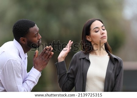 Man with black skin begging forgive and caucasian woman rejecting him in a park Сток-фото © 