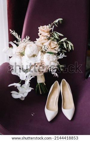 Wedding details of the bride. А bouquet of flowers with a ribbon and women's shoes with heels lie on a purple chair  Сток-фото © 