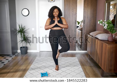 young african black woman keep balance, stand on one leg, yoga time at home. concentrated on yoga, meditation