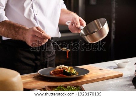 Professional Chef-cook Decorating Dish In Restaurant Kitchen Alone. Man In White Apron Makes Finishing Touch On DIsh. Culinary, Restaurant, Gourmet Concept Foto stock © 