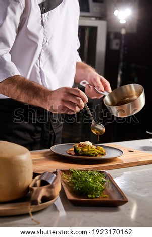 Cook adding some sauce to dish. Cropped chef preparing food, meal, in kitchen, chef cooking, Chef decorating dish, closeup