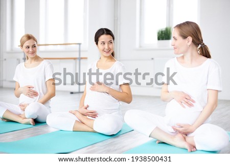 Asian and european pregnant women sit on fitness mat having conversation Imagine de stoc © 