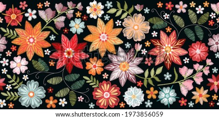Colorful seamless embroidery border with bright flowers and leaves. Floral embroidered pattern on black background. Fashion print.