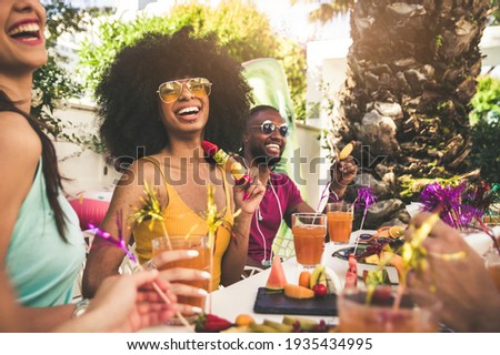 Multiracial group of friends having fun at backyard home party - Young people laughing together drinking cocktails at bar restaurant - Focus on black woman