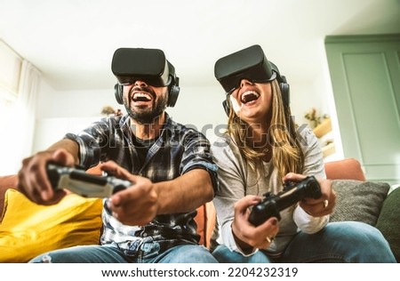 Similar – Image, Stock Photo Friends playing video game at home. Gamers playing online in dark room lit by neon lights. Competition and having fun