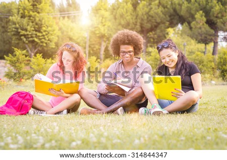 three students are studying sitting at the park - people, lifestyle and nature concept